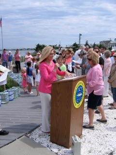 A woman in a pink outfit addresses an audience